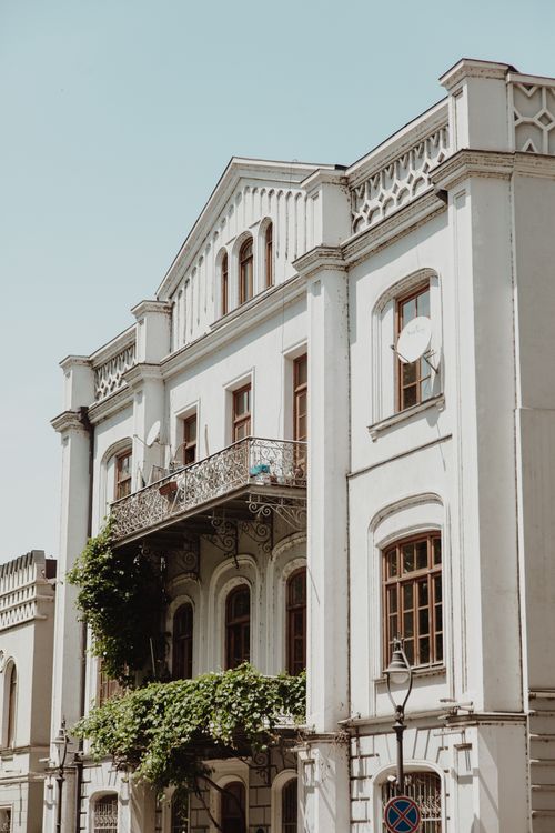 Free Elegant building facade in Tbilisi with arched windows and balcony showcasing classic Georgian architecture. Stock Photo