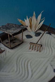 Serene miniature Zen garden with sand raked into patterns, rocks, and a small wooden rake for relaxation.