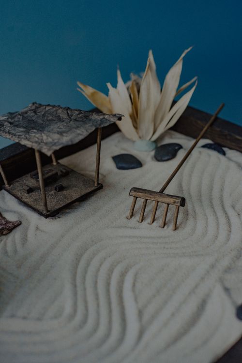 Free Serene miniature Zen garden with sand raked into patterns, rocks, and a small wooden rake for relaxation. Stock Photo