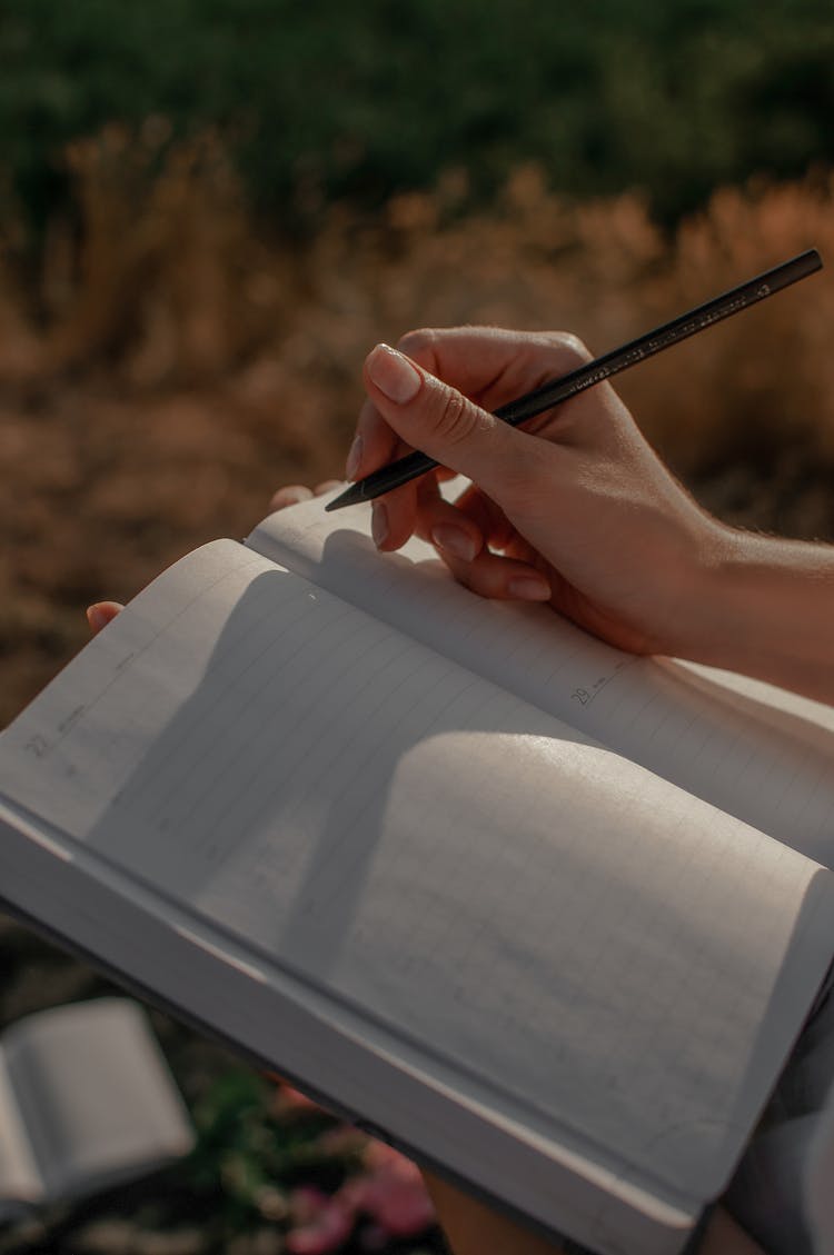 Close-up Of Woman Writing In A Journal Outdoors 