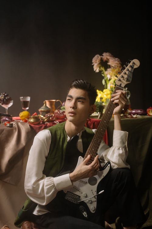 Free Young man with electric guitar posing in a stylish studio with elegant decor. Stock Photo