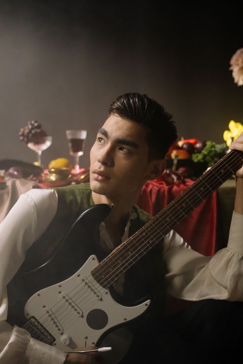 Free A young musician poses with an electric guitar in an artistic indoor setting. Stock Photo