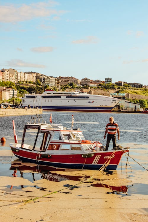 An Elderly Man Standing on a Red Motorboat