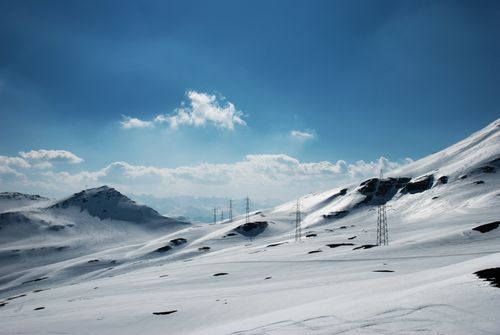 Free Scenic view of snowy mountains under a clear blue sky, featuring power lines. Stock Photo