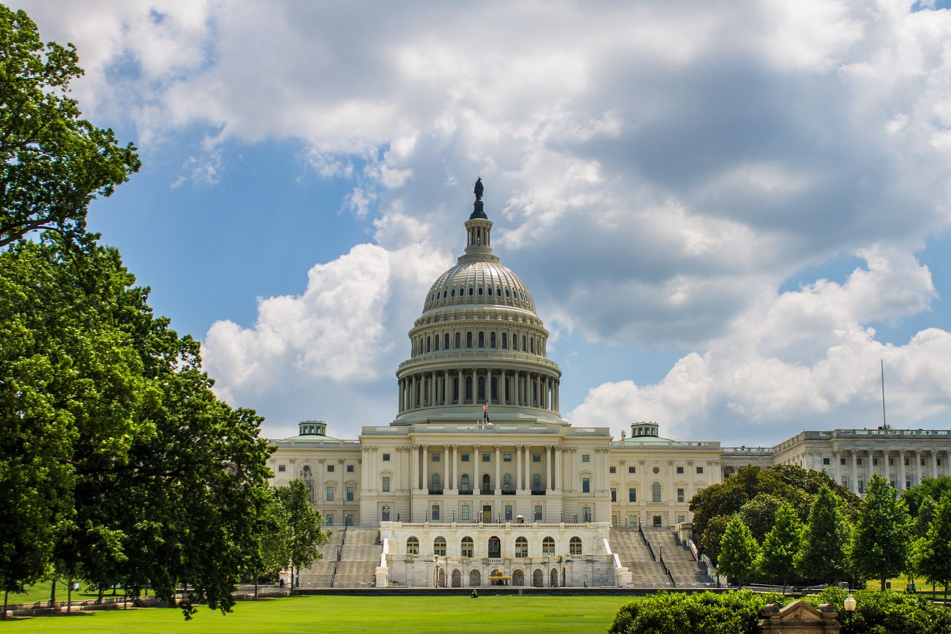 Historic view of the United States Capitol under a blue sky, showcasing iconic architecture.