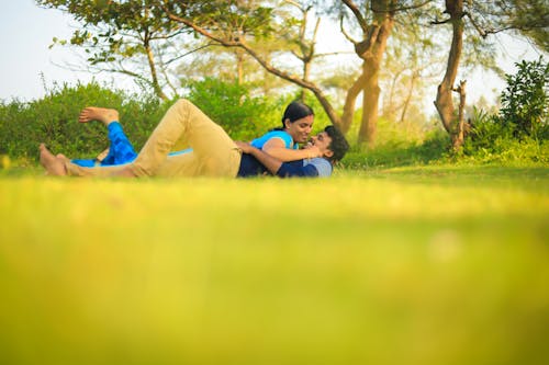 Free A Couple Lying on the Grass while Looking at Each Other Stock Photo