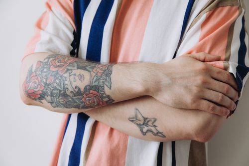 Free Colorful tattooed arm wearing a striped shirt with crossed arms pose. Stock Photo
