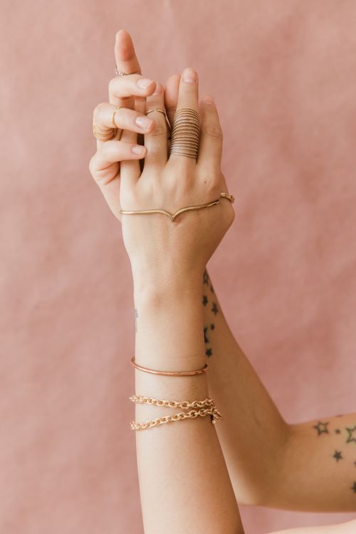 Free Close-up of hands adorned with jewelry and tattoos on a pink background, showcasing style and elegance. Stock Photo