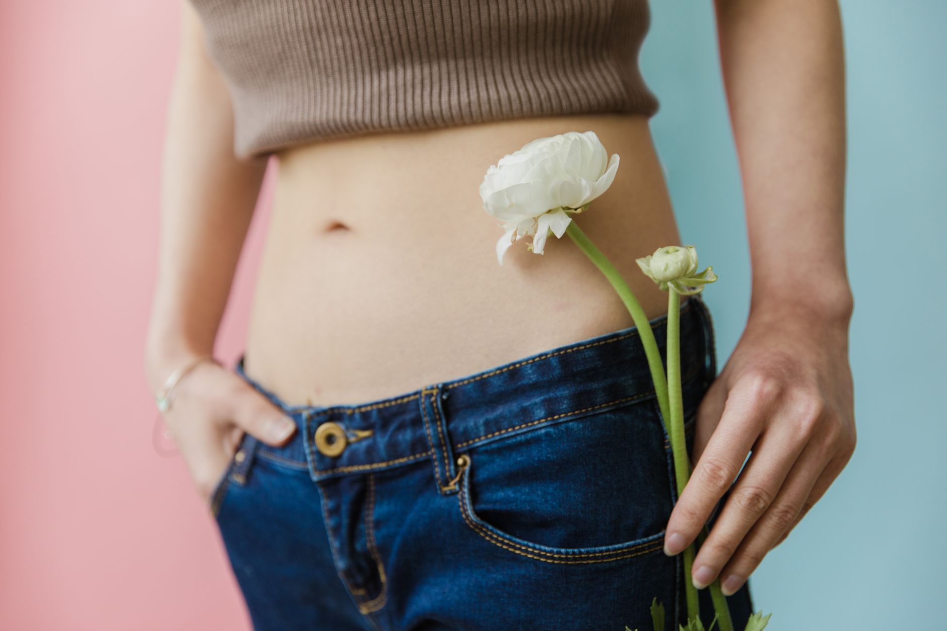 natural gut repair after long covid — Close-up of a woman in a brown top and jeans holding a white flower.