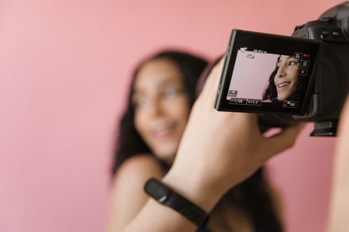 Free Close-up of woman smiling during a studio photoshoot with a pink backdrop. Stock Photo