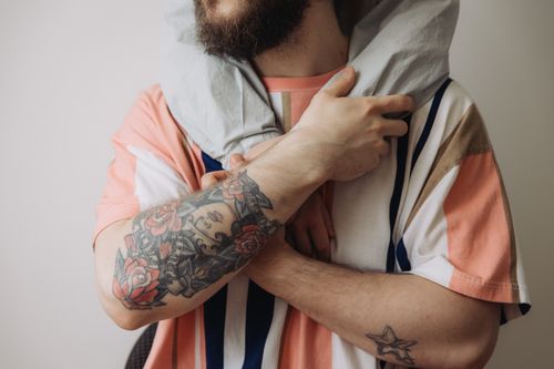 Free Close-up of tattooed man in patterned t-shirt embracing with a personal touch. Stock Photo