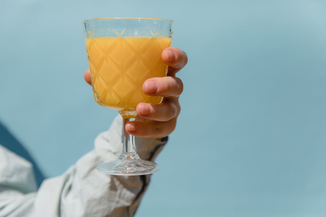 Free Person Holding Clear Glass of Orange Juice Stock Photo