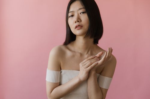 Free Sophisticated portrait of a woman with short hair posing against a soft pink backdrop. Stock Photo