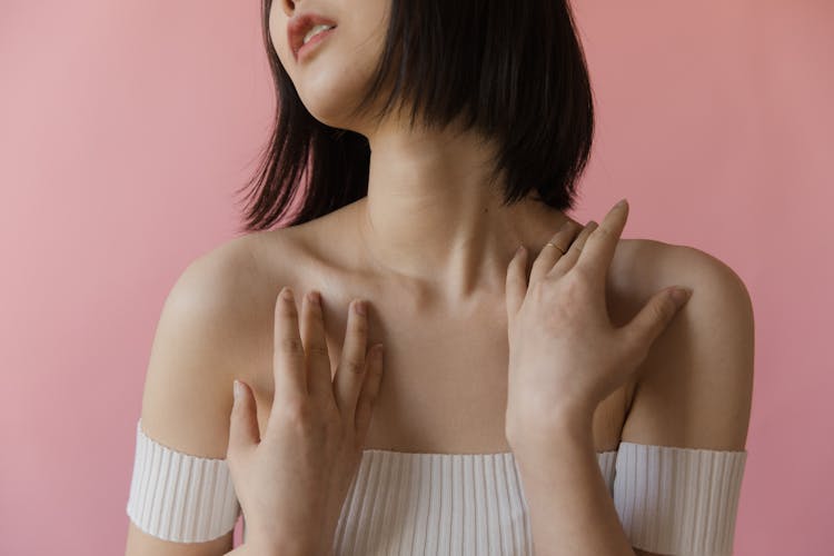 A Woman In White Off Shoulder Top With Her Hands On Her Shoulders