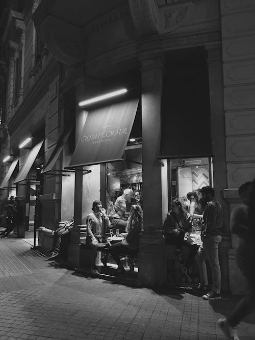 People Sitting Outside of a Bar in the Evening 