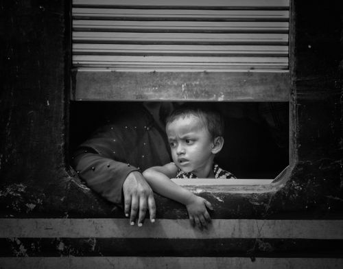 Free A thoughtful child gazes out of a train window, capturing a moment of travel and contemplation. Stock Photo