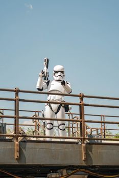 Stormtrooper in costume poses on a metal platform against a clear blue sky, outdoors.