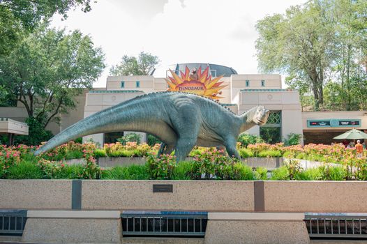 Dinosaur statue in lush garden at Disney's Animal Kingdom, Florida.