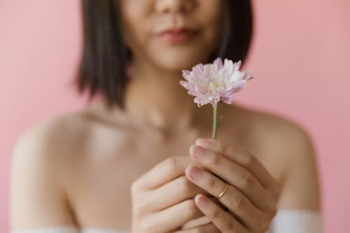 A Person with Short Hair Wearing Ring while Holding Pink Flower