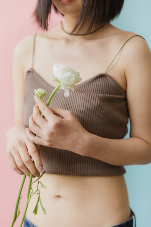 A Woman in Brown Tank Top Holding a Flower