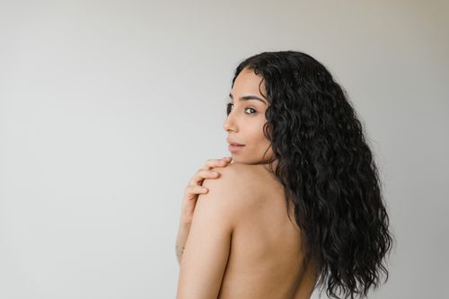 Free Studio portrait of a topless woman with curly black hair and serene expression. Stock Photo