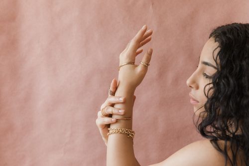 Free Close-up of a woman with gold jewelry against a pink background, highlighting elegance and style. Stock Photo