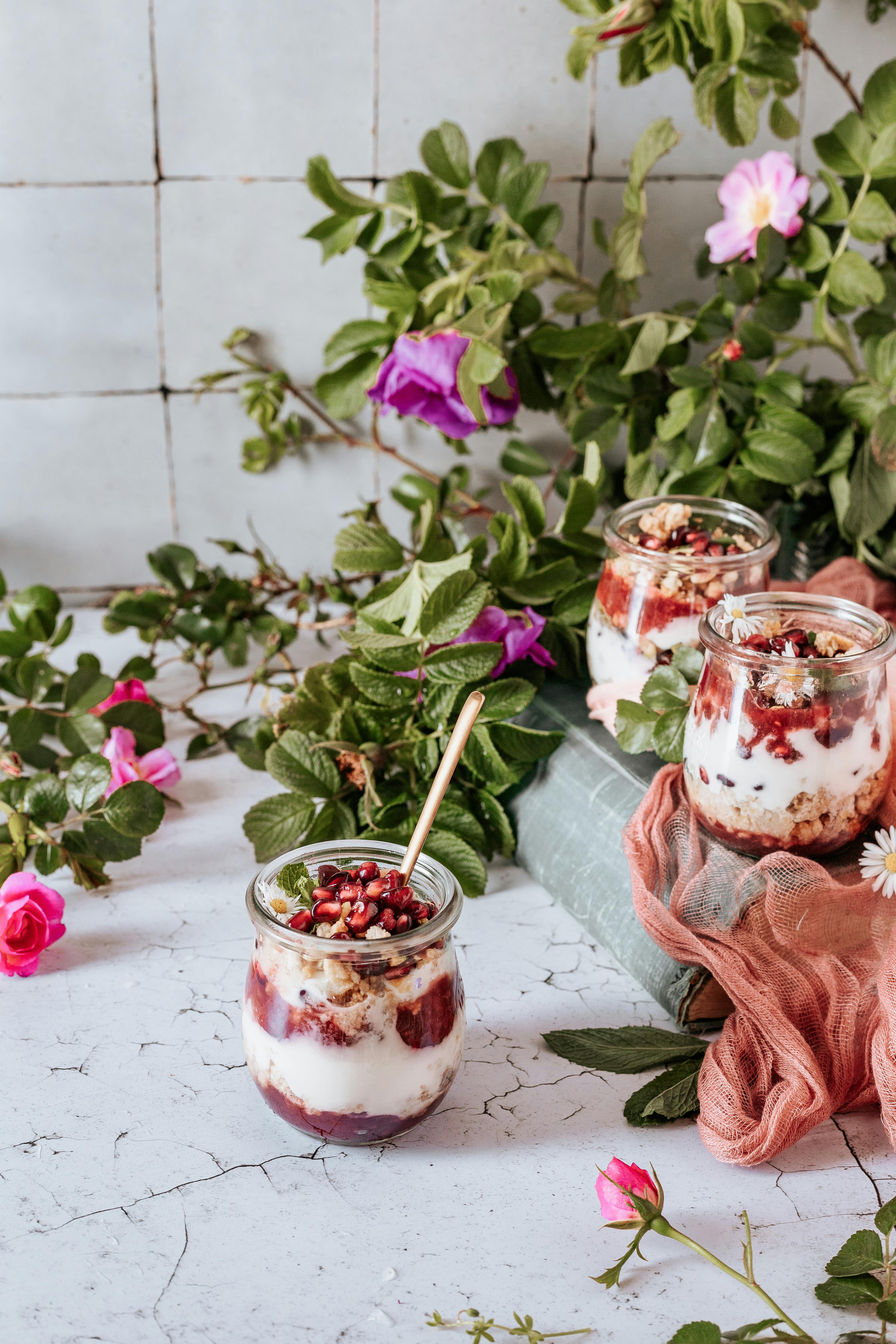 Elegant yogurt parfaits garnished with pomegranate seeds and flowers, perfect for a refreshing dessert.