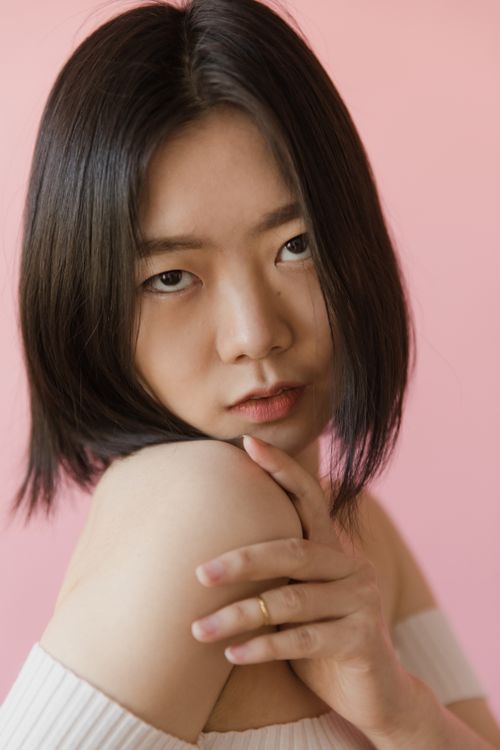 Free Close-up portrait of a young woman with black hair and a pink background. Stock Photo