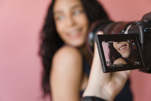 Close-up of a woman being photographed, focus on camera screen.