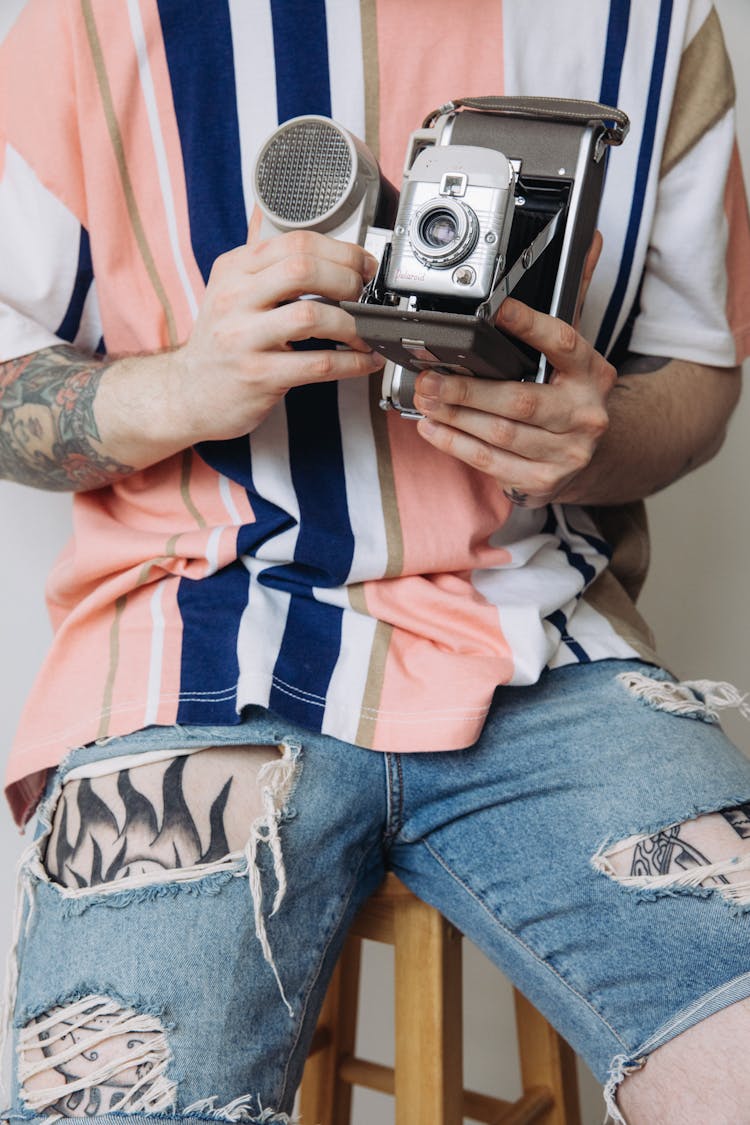 Close-up Of Man In Ripped Jeans Holding A Vintage Polaroid Camera 