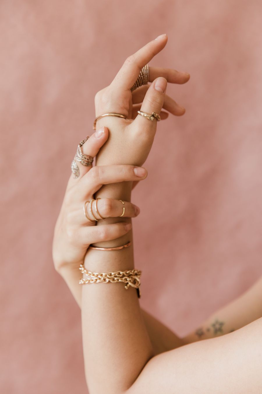 Gold bracelet and rings stacked on the wrist