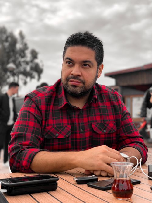 Free Bearded man in a red and black checkered shirt sitting outdoors with a cup of tea. Stock Photo