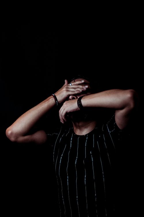 Free Dark portrait of a man covering his face with hands. Moody and mysterious atmosphere. Stock Photo