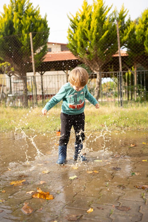 Young Boy Wearing Sweater Playing on Water