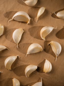 Flat lay of garlic cloves on brown paper, perfect for food and cooking themes.