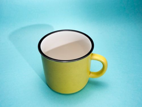 Free Empty yellow ceramic mug on a light blue background with shadow play, offering ample copy space. Stock Photo