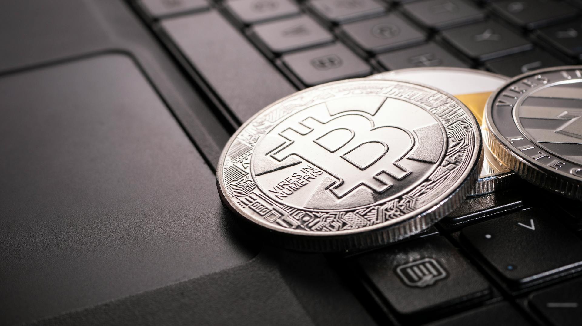 Close-up of Bitcoin and cryptocurrency coins on a laptop keyboard representing digital currency and finance.