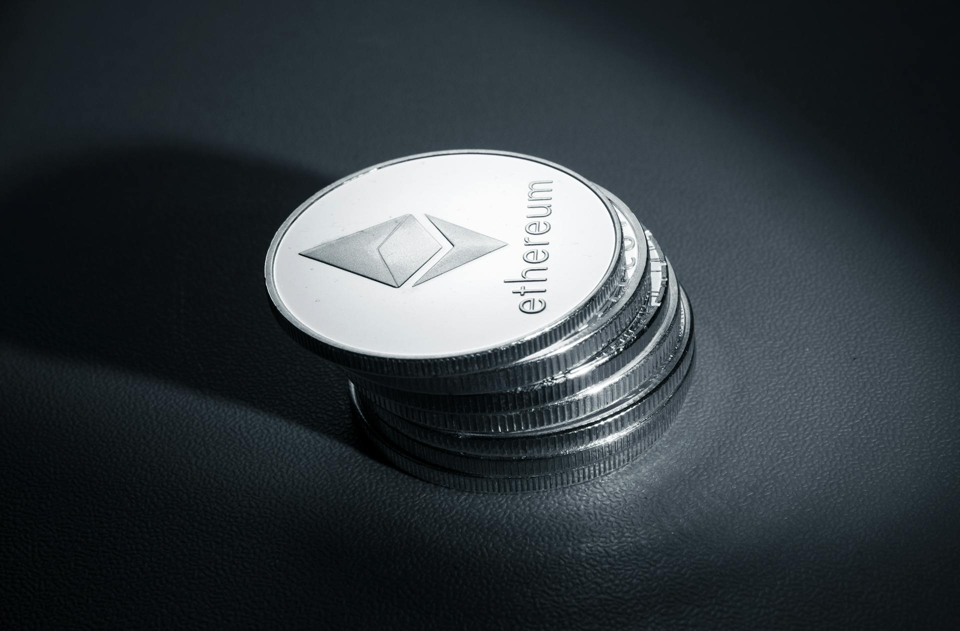 Close-up of stacked Ethereum coins on a dark textured surface, symbolizing modern cryptocurrency.