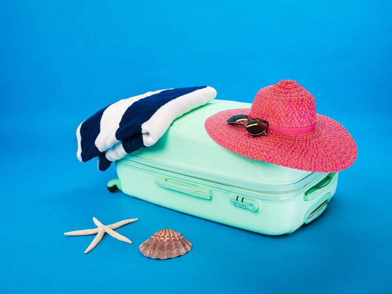 Cabin suitcase and beach essentials on a blue backdrop — Kindel Media on Pexels