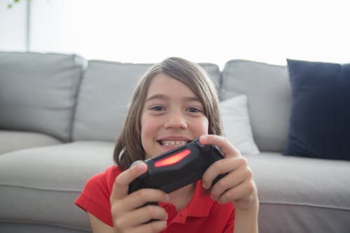 Boy in Red Polo Shirt Holding Black Game Controller