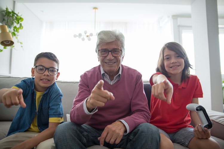 Elderly Man And Kids Sitting On Gray Sofa