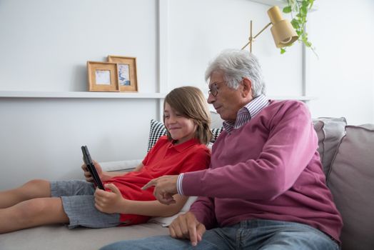 Elderly Man and a Boy Looking at the Screen of a Tablet