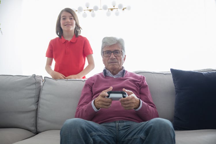 Elderly Man Sitting On Sofa While Playing Video Game