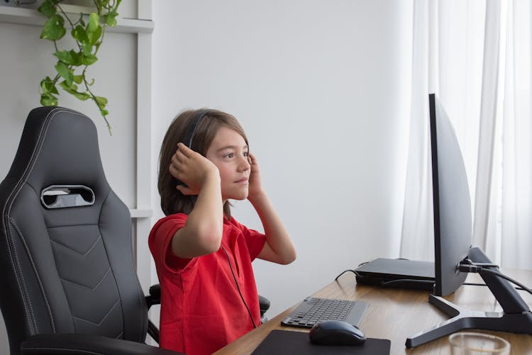 Boy In Red Shirt Sitting On Gaming Chair In Front Of The Computer