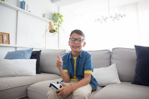 Boy Sitting on Sofa While Holding Video Game Controller