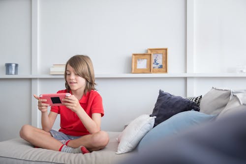 Boy Sitting on Sofa While Playing Video Game