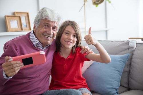 Free Grandfather and granddaughter sharing a joyful moment at home, capturing a selfie together. Stock Photo