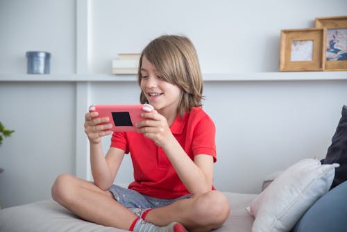 Boy Smiling While Playing a Tablet