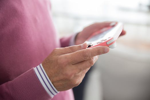 Adult in pink sweater playing with handheld game console indoors, showcasing modern technology and leisure.