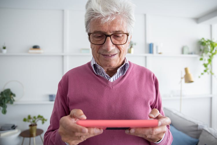 Elderly Man Playing On Portable Console